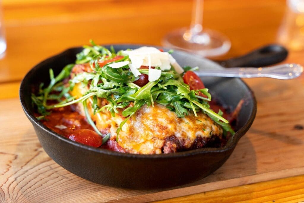 A pan of food with cheese and vegetables on top.