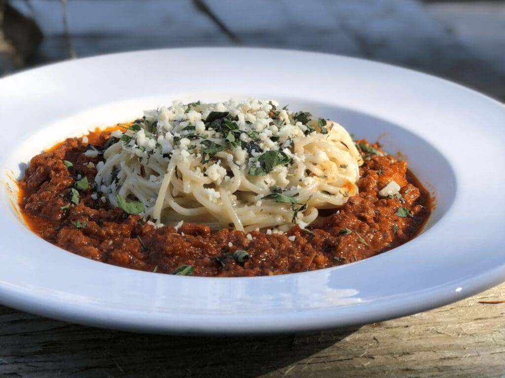 A white plate topped with pasta covered in sauce.