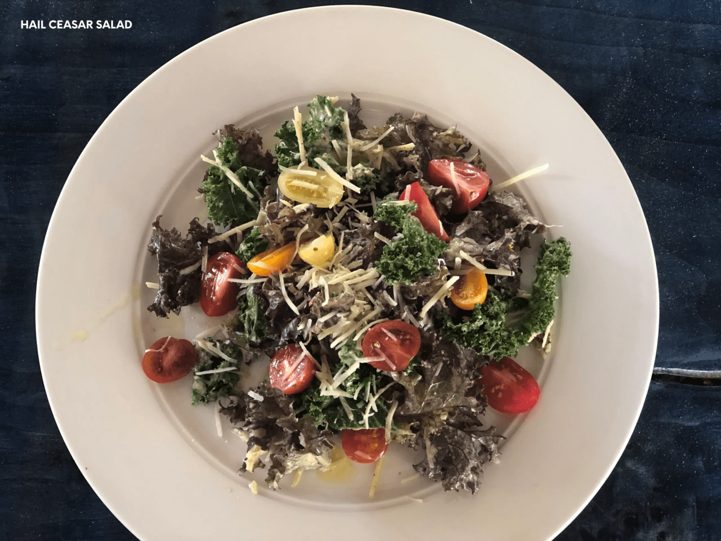 A white bowl of salad with tomatoes and broccoli.