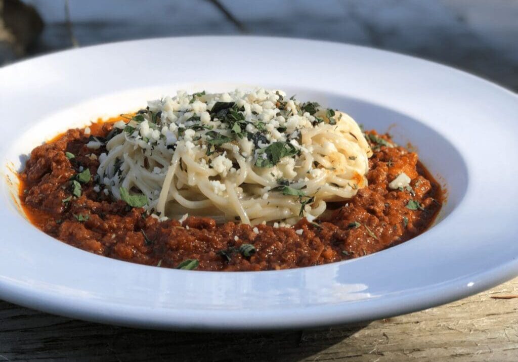 A white plate topped with pasta covered in sauce.