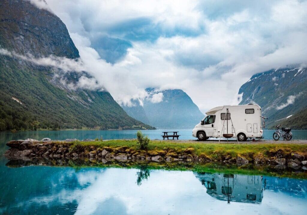 A white rv parked next to the water.